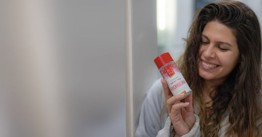 Frau mit Perückenstrauch-Mundwasser Hydrolina vor dem Spiegel, Pflege bei Aphthen auf der Zunge